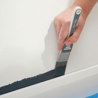 small paint brush being used to paint a wall