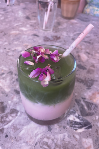 Benefits of matcha: a matcha green tea latte with the matcha separate from the pink milk and rose petals on the top
