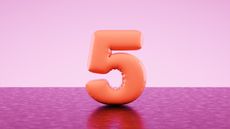 An orange balloon in the shape of the number five against a two-toned pink background.
