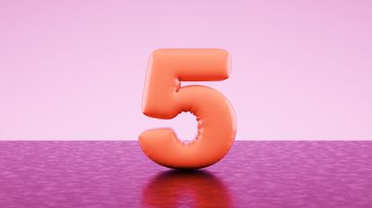 An orange balloon in the shape of the number five against a two-toned pink background.