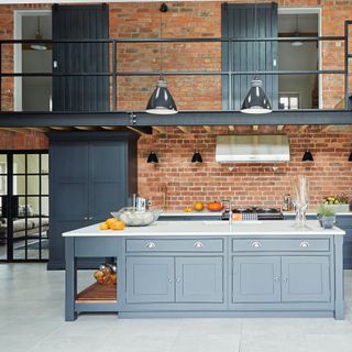 Kitchen with exposed brick walls, grey cabinetry and mezzanine hallway
