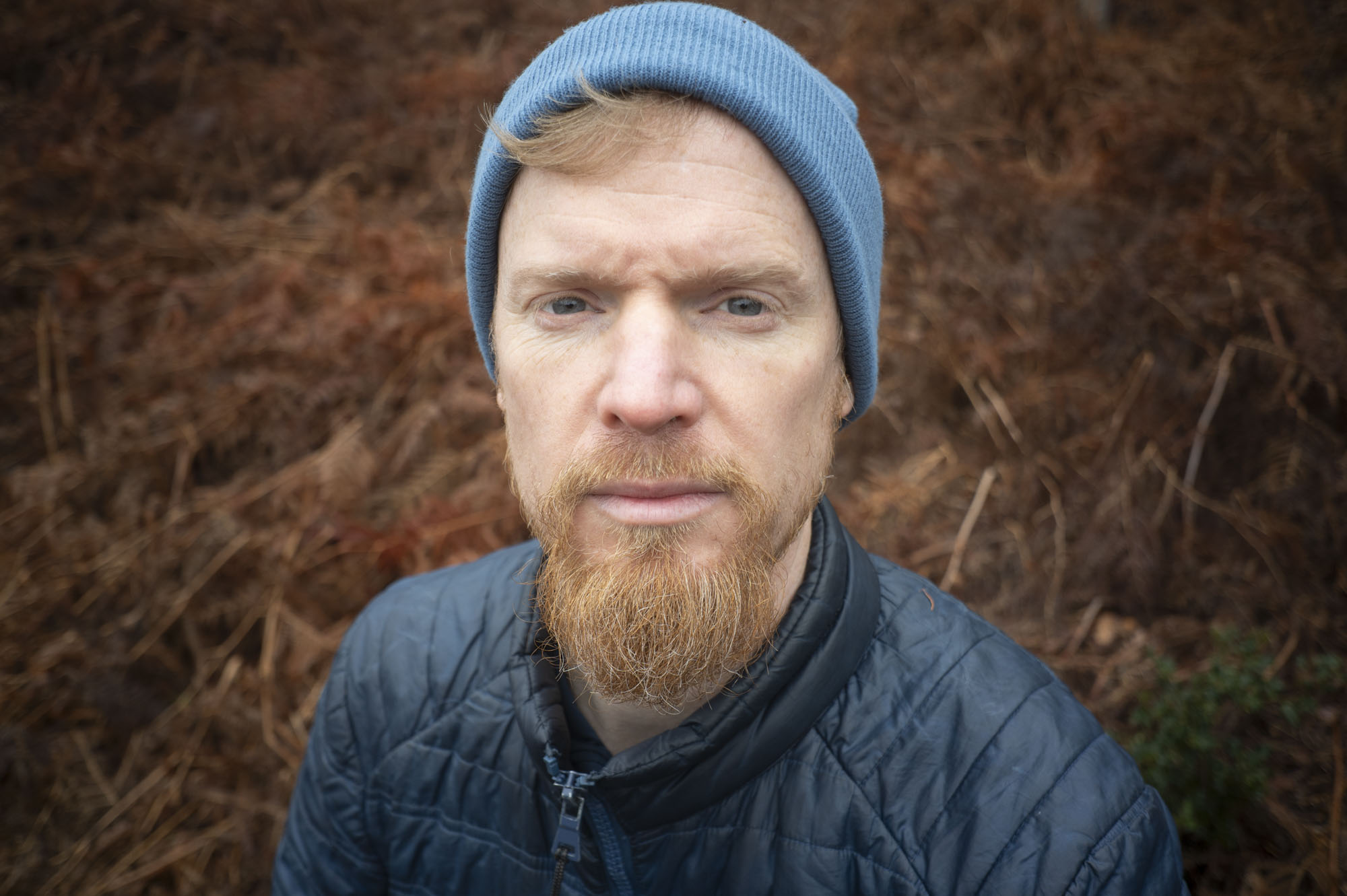Viltrox AF 28mm F4.5 image gallery: man in blur beanie hat with autumnal ferns behind him