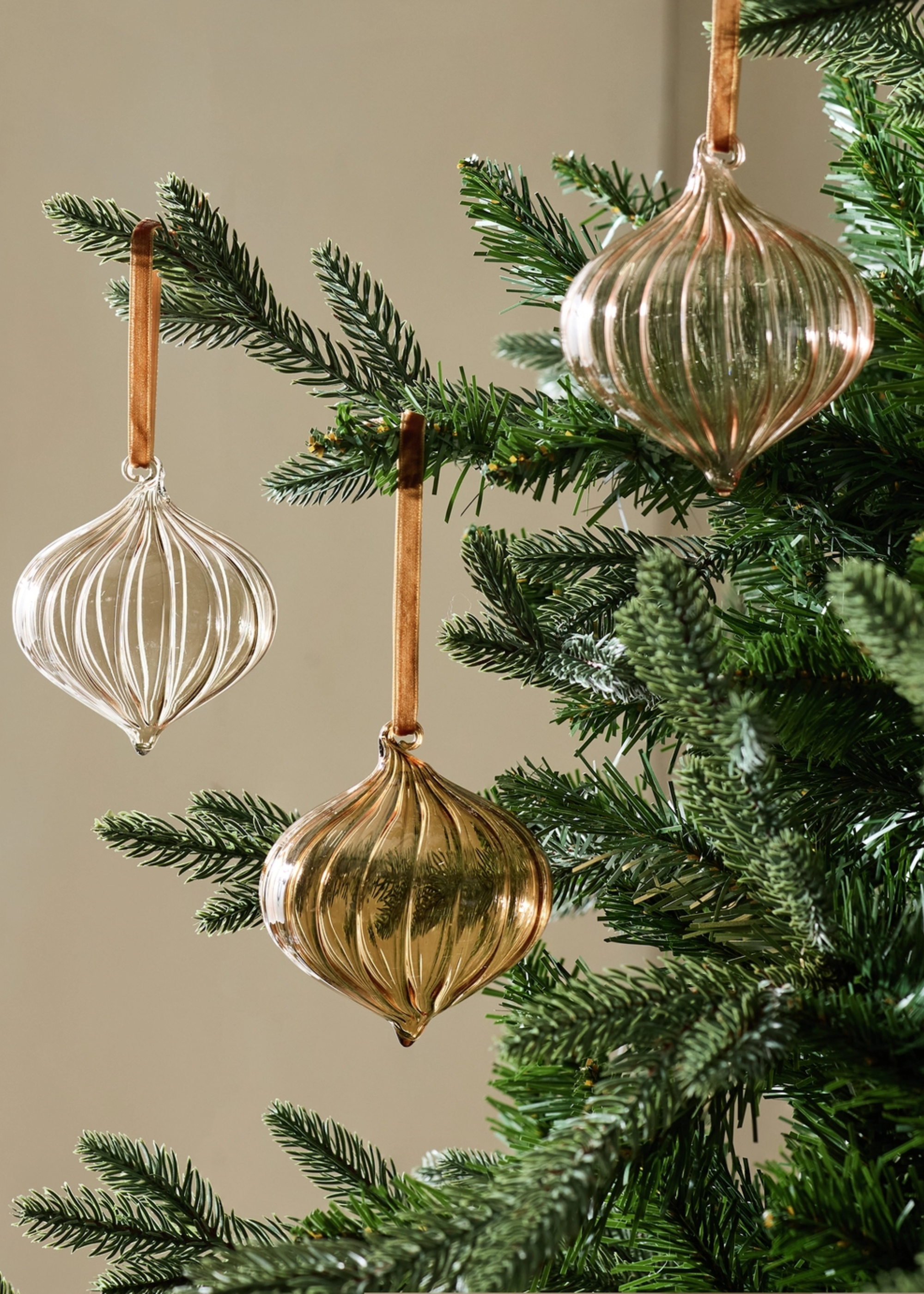 A close-up of a Christmas tree with glass baubles on velvet ties