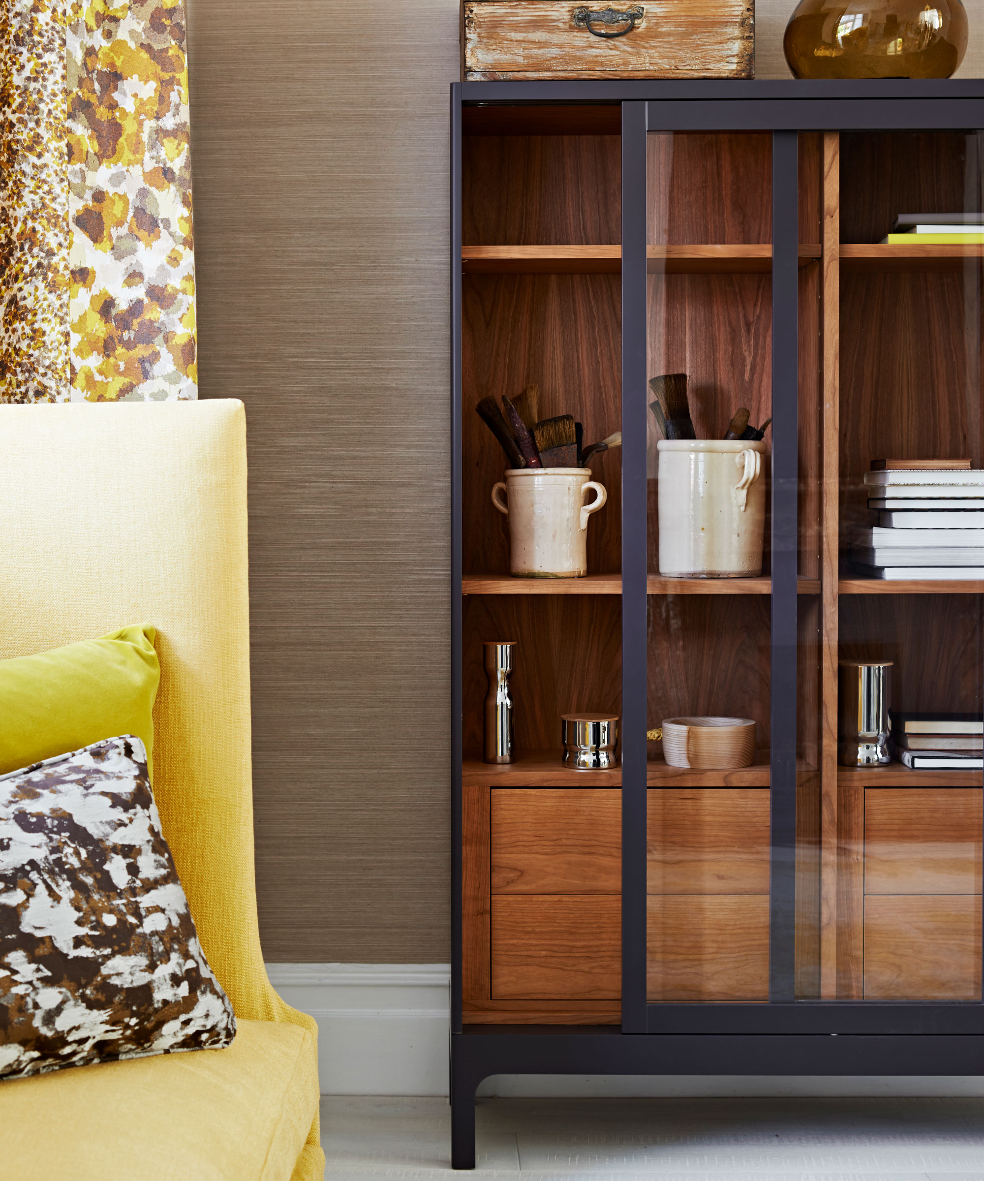 How to style a display cabinet - wooden glass fronted dresser with black painted edges and yellow sofa and decorative curtains