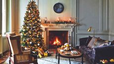 Living room with purple sofa, cream armchair, marble fireplace and lit Christmas tree