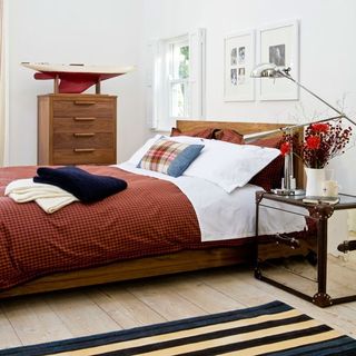 bedroom with white wall and wooden flooring with travelers trunk.