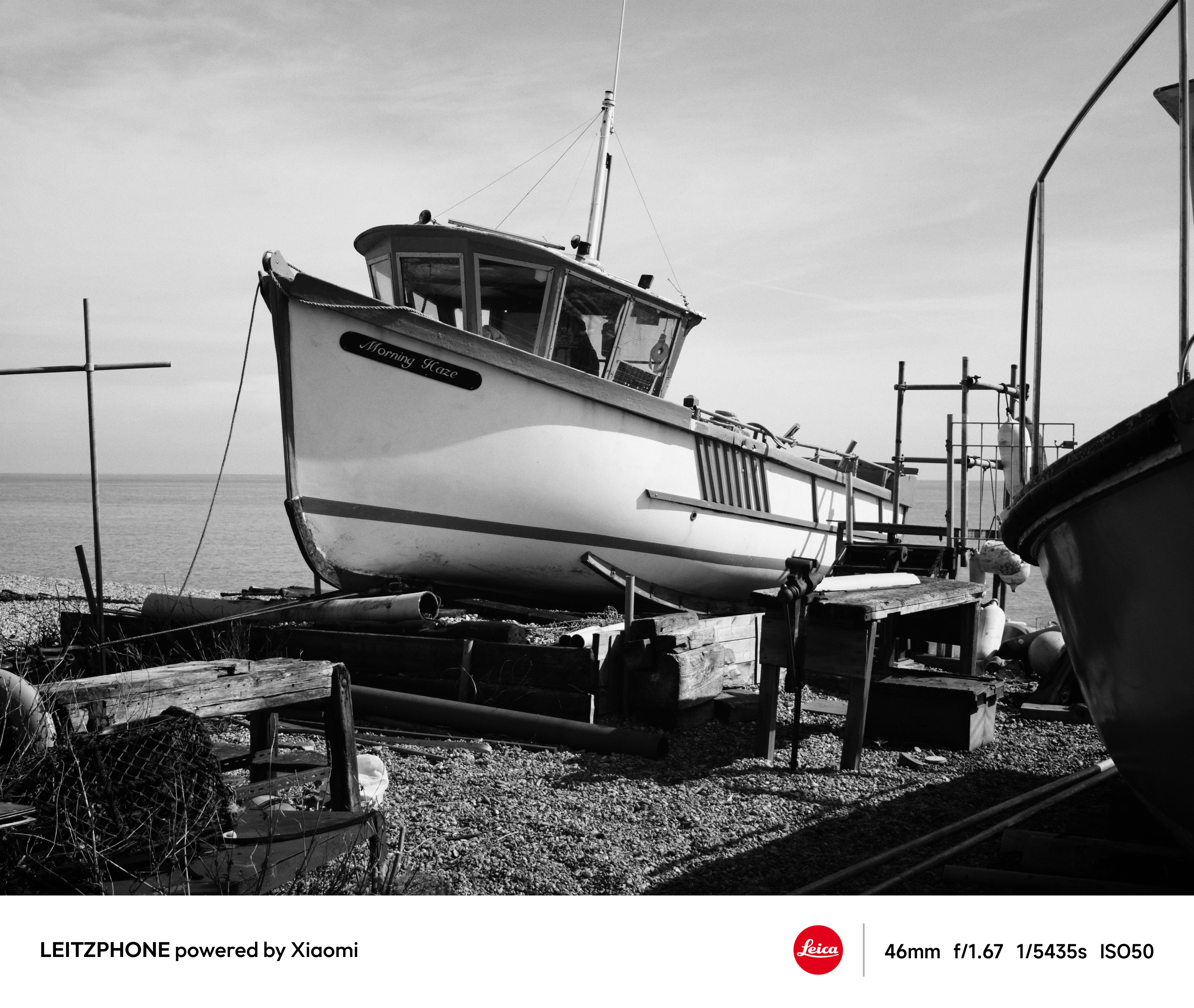 Black-and-white photo of a fishing boat on a pebble beach