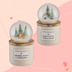 Aldi snow globe candles on a pink background.