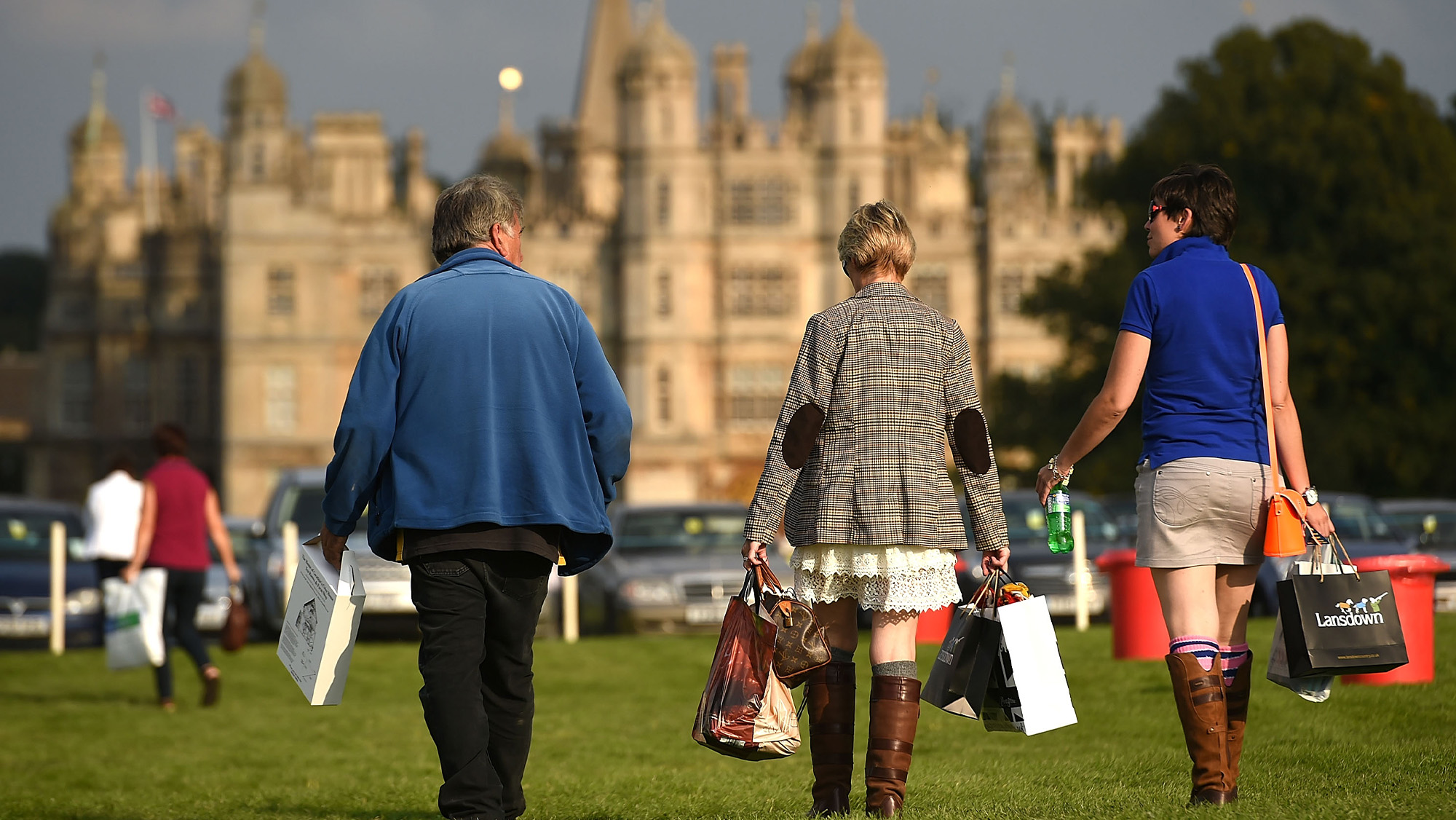 Three shoppers walk towards Burghley House after shopping at Burghley Horse Trials