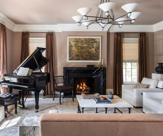 muted pink living room with a large grand piano and a black marble fireplace with a framed tapestry hung above the mantel