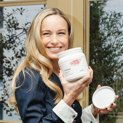 Brie larson smiling and holding a white jug