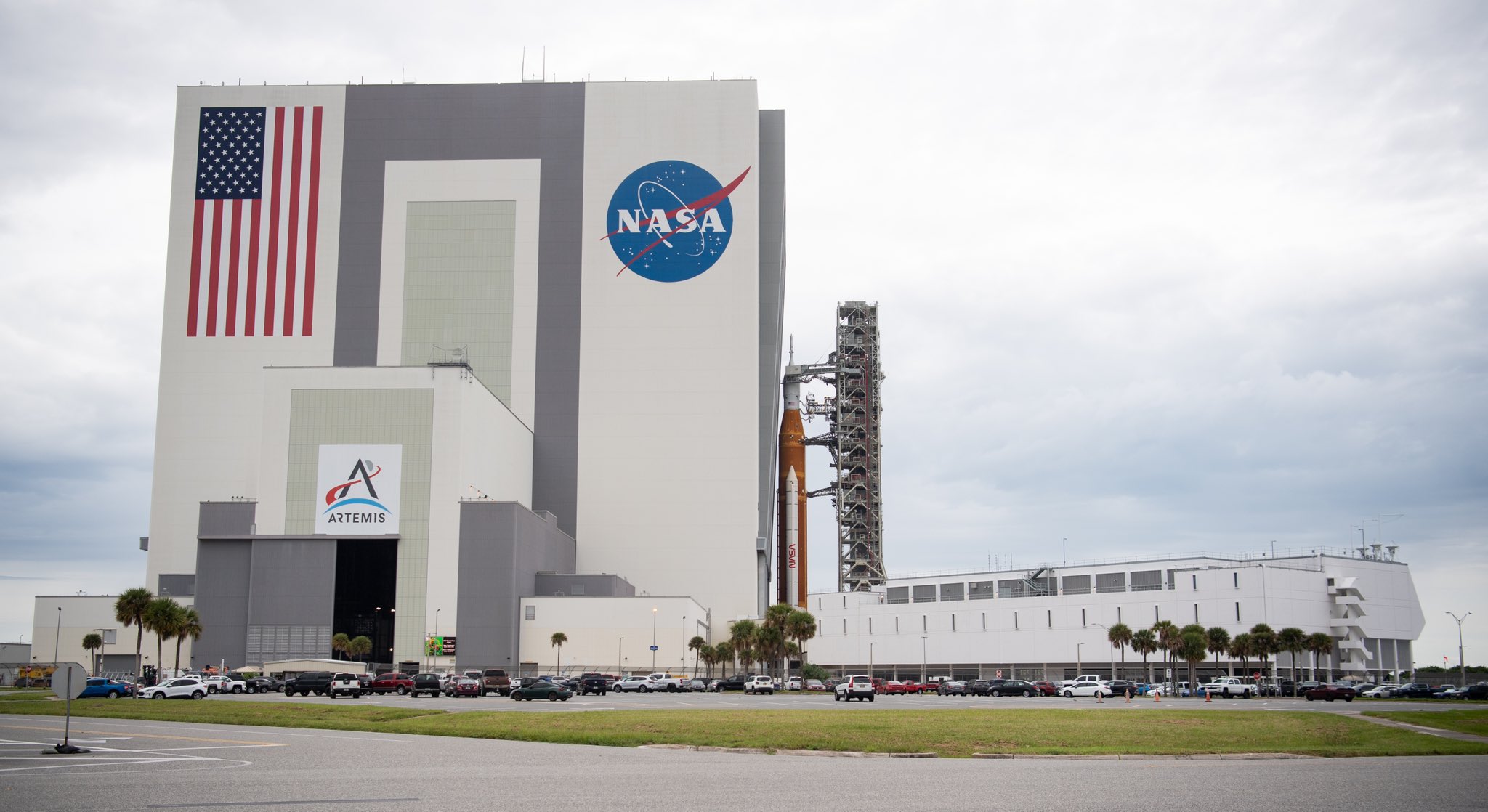 a huge orange rocket being wheeled into a massive white building