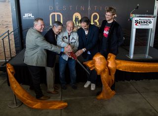 Buzz Aldrin cut a ceremonial ribbon for the new "Destination: Mars" program at Kennedy Space Center Sept. 18, 2016, along with Therrin Protze, chief operating officer of the visitor complex, and Bob Cabana, the center's director, on Aldrin's left. Kudo Tsunoda of Microsoft and Jeff Norris of NASA's Jet Propulsion Laboratory are on the astronaut's right.
