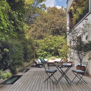 Garden with shaded decking area and garden furniture on it.