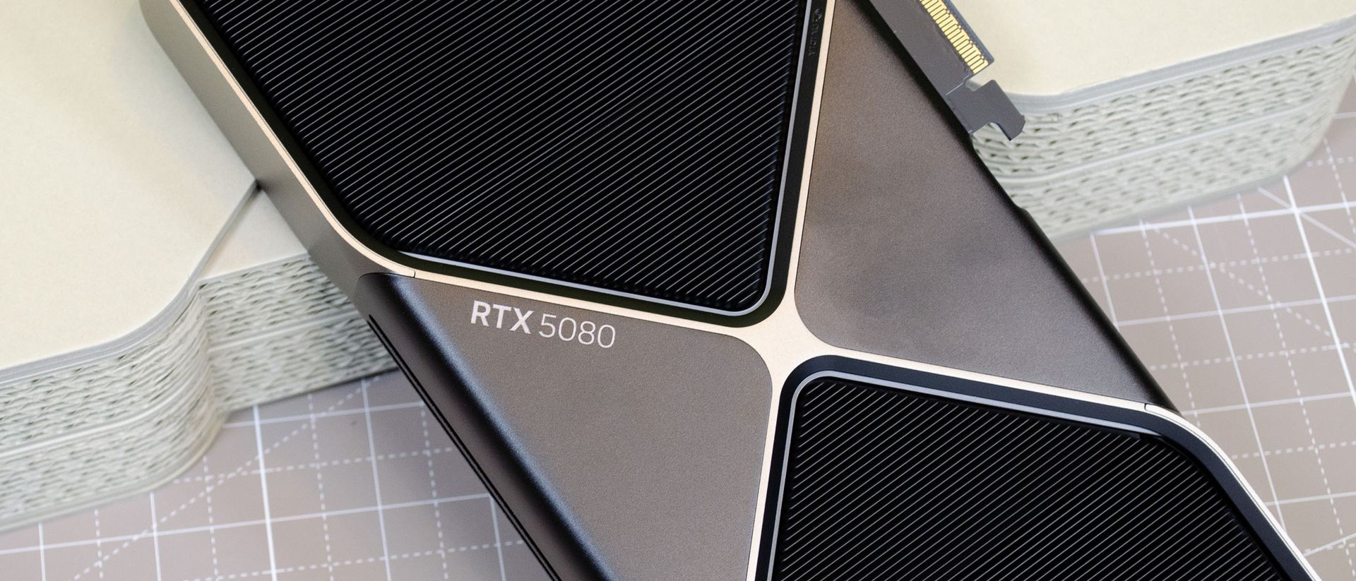 An Nvidia GeForce RTX 5080 leaning against its retail packaging with the RTX 5080 logo visible