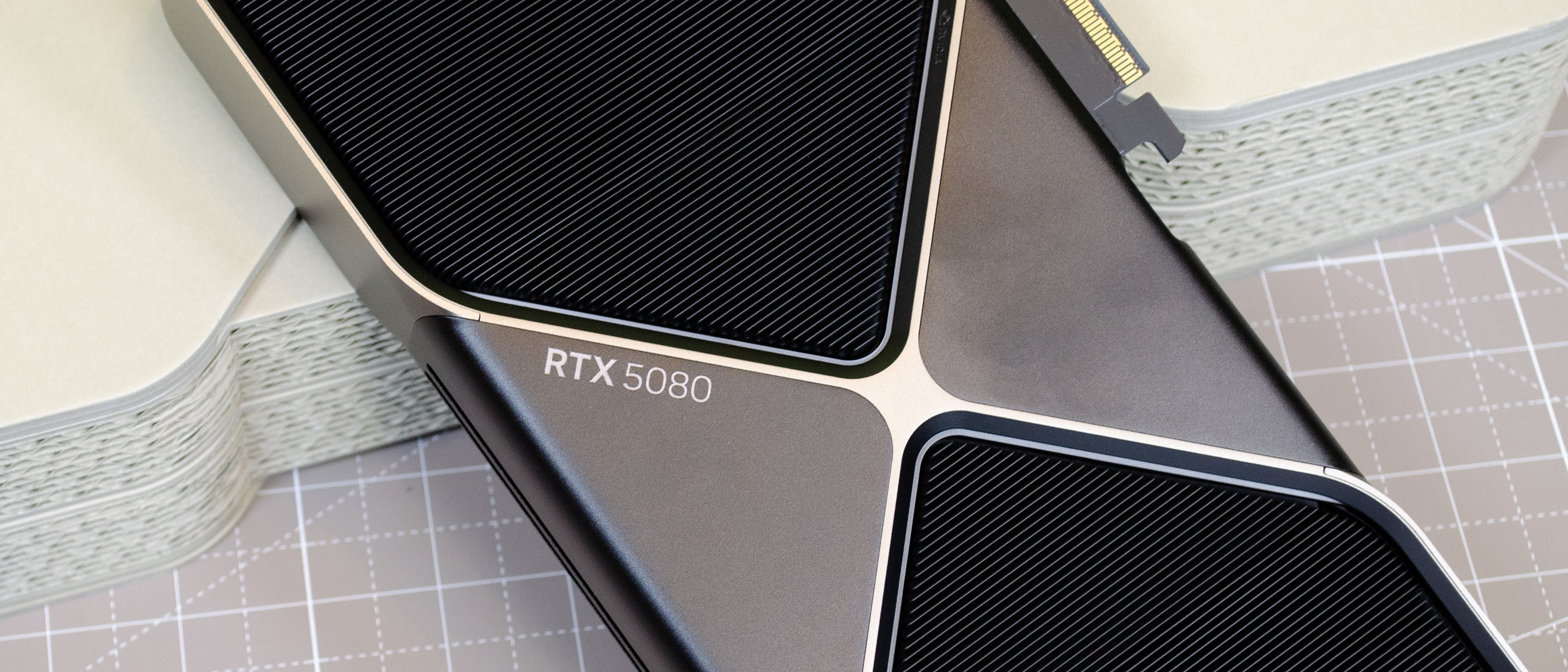An Nvidia GeForce RTX 5080 leaning against its retail packaging with the RTX 5080 logo visible