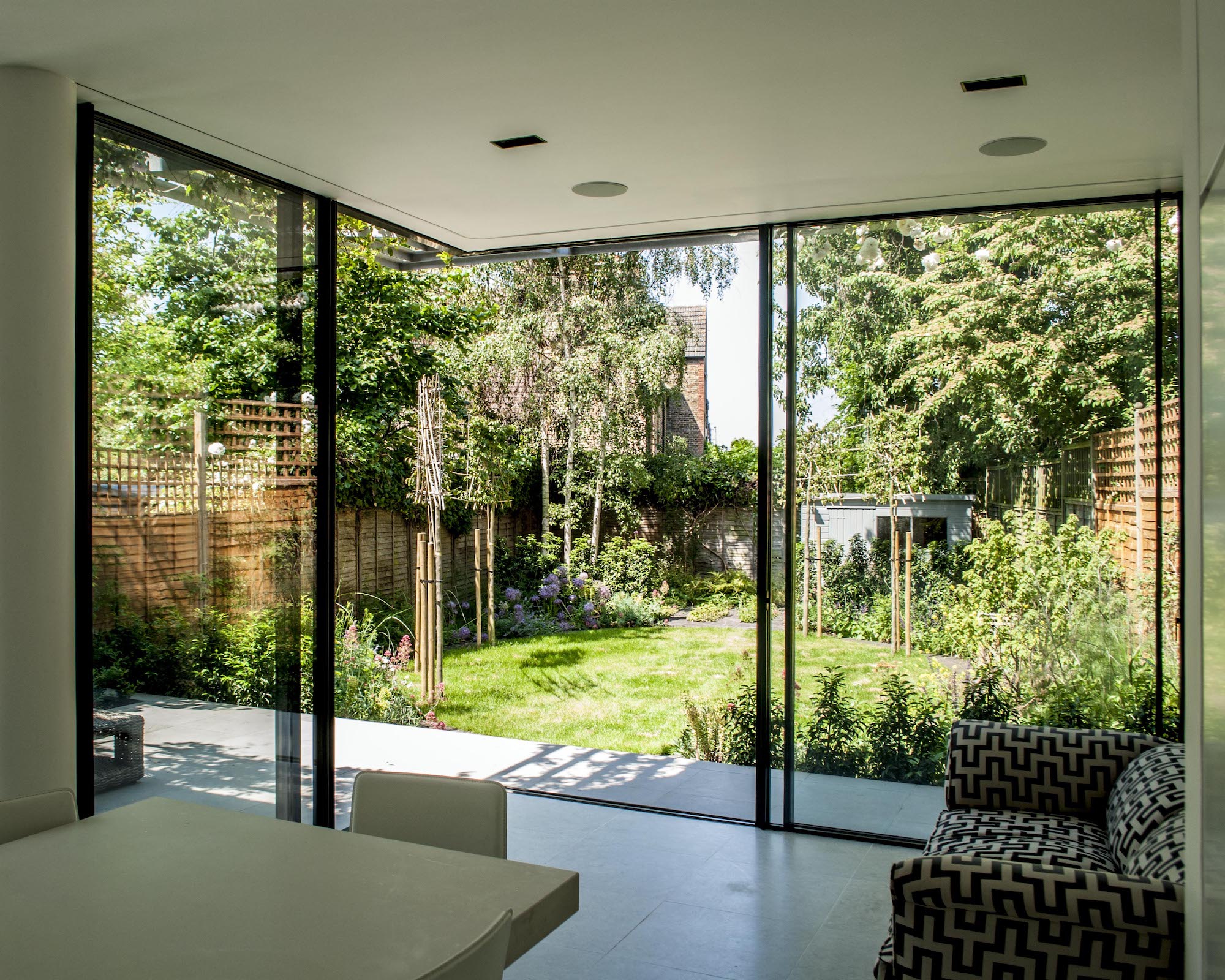Dining-living space with outlook to garden through sliding glass doors with opening corner
