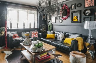 Dark living room with black painted walls, leather sofas and a wooden table, all with a modern eclectic look