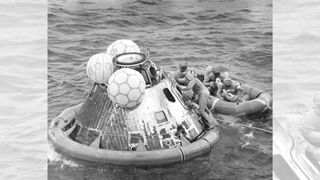 Men in white suits climb aboard the Apollo 11 crew capsule after it splashed down in the Pacific Ocean