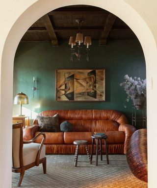 dark green painted snug small living room with wooden panelled ceiling and vintage furniture