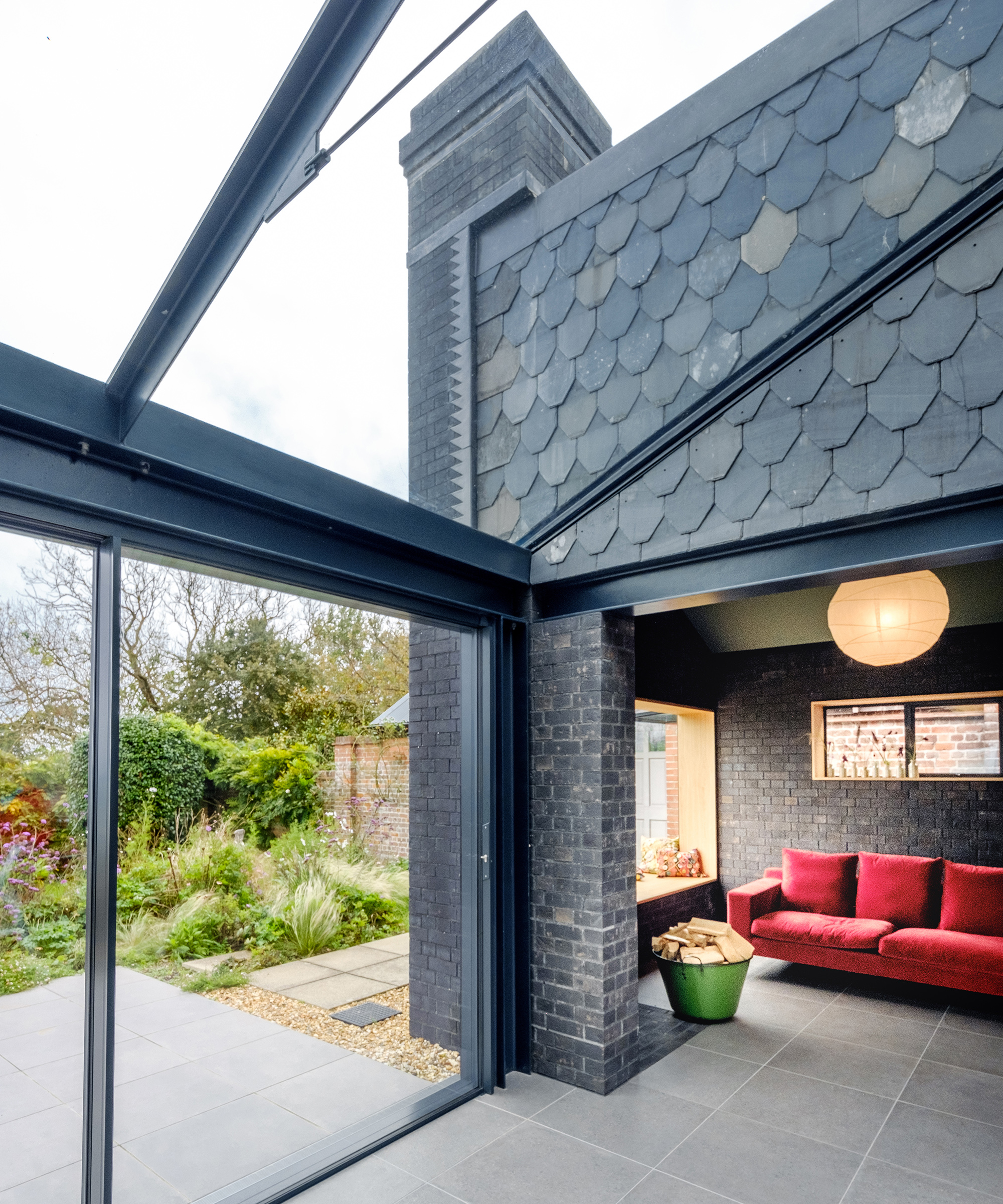 Glass roof link extension leading to a relaxed seating area with red sofa