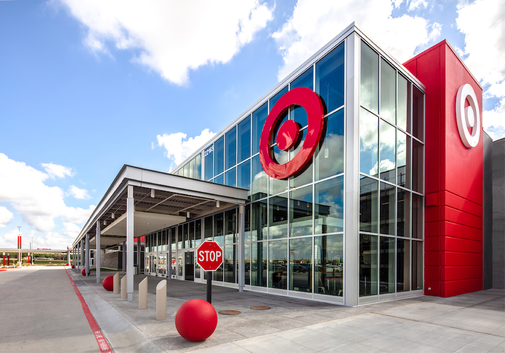 An exterior view of a modern Target department store with a glass and red facade featuring the large red bullseye logo against a blue sky.