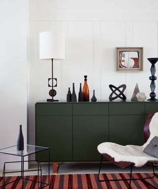 Green sideboard with sculptural lamp and stripe rug