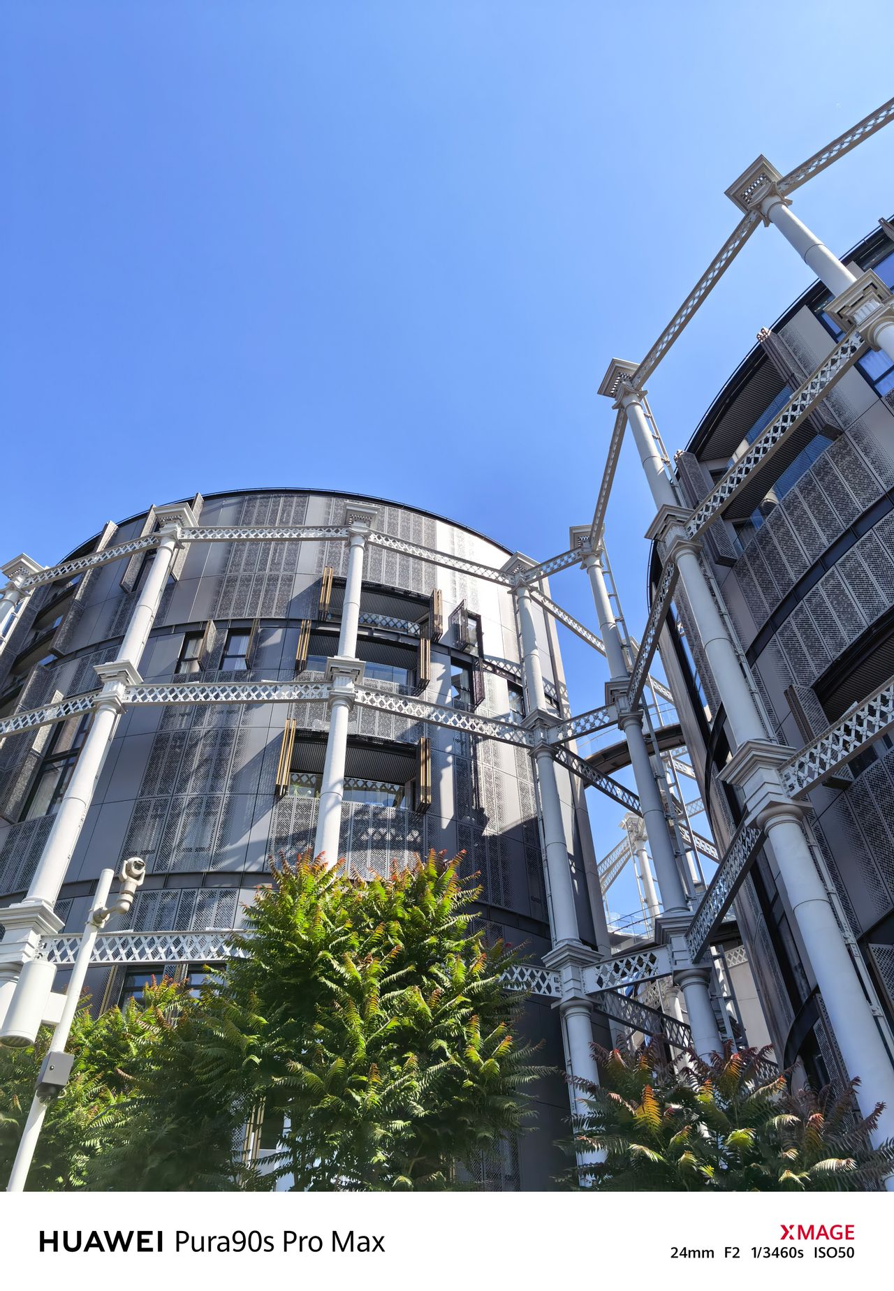 Upward view of modern cylindrical apartment buildings enclosed by the white metal framework of former gas holders.