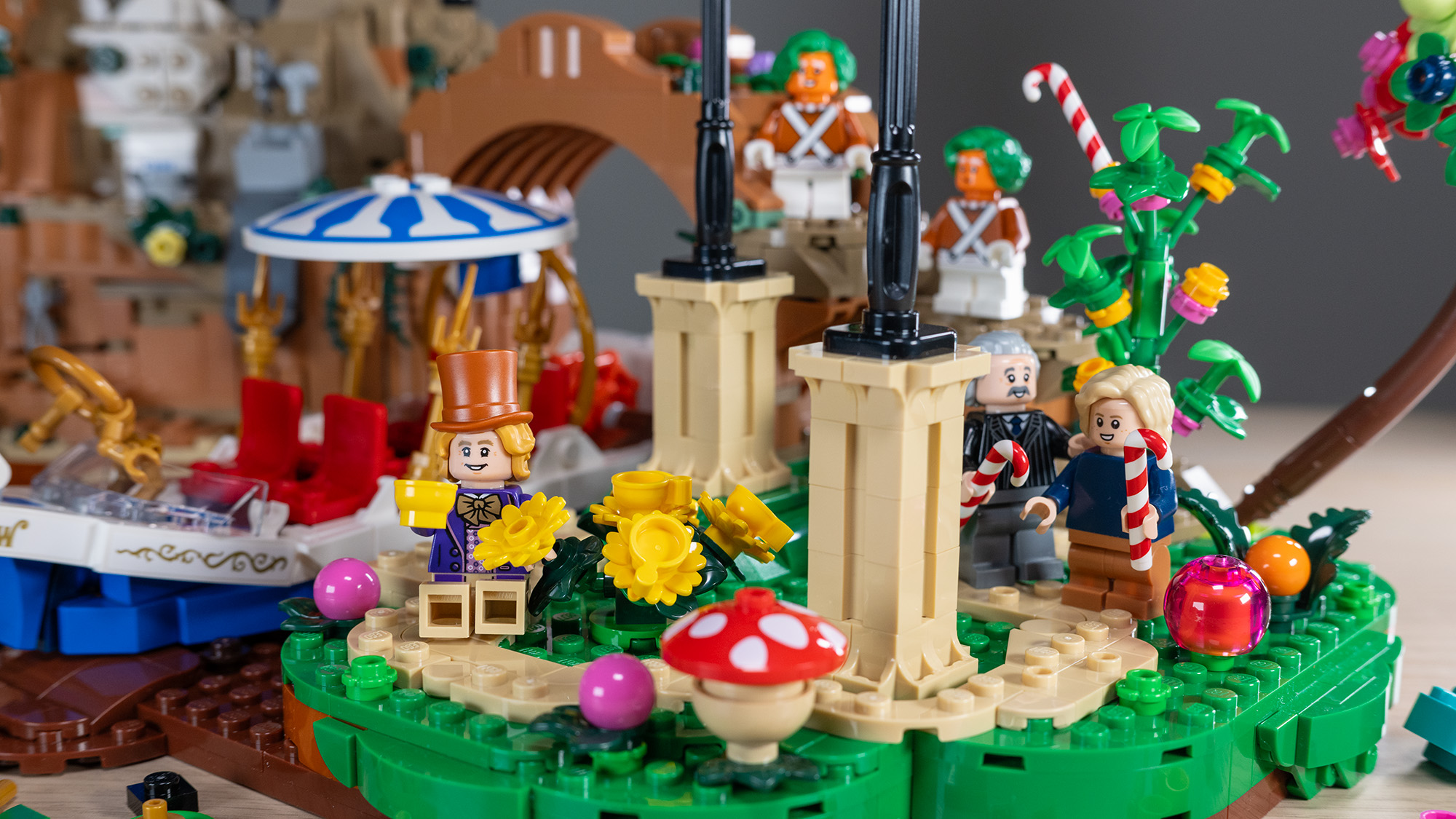 Lego Ideas Willy Wonka & the Chocolate Factory (21360) set, close-up of Willy Wonka eating edible teacup, with Charlie and Grandpa Joe holding candy canes.