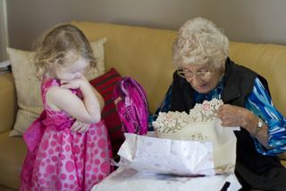 a girl watches old lady open a present