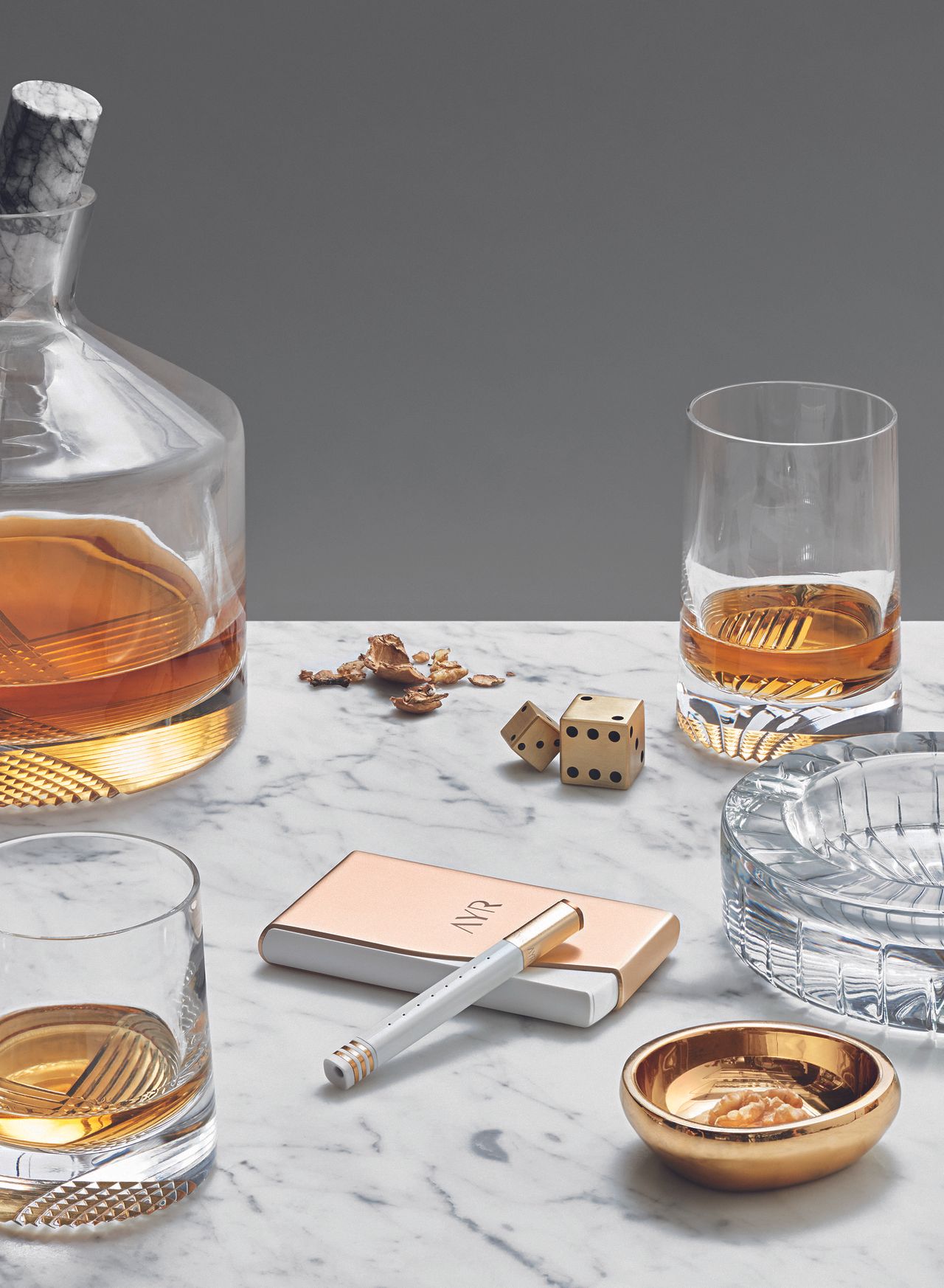 Whisky carafe, glasses, Dice, ashtray and vape on a marble table