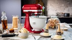 The KitchenAid Ice Cream Maker Attachment on a red stand mixer with ice cream organised in different ways around it