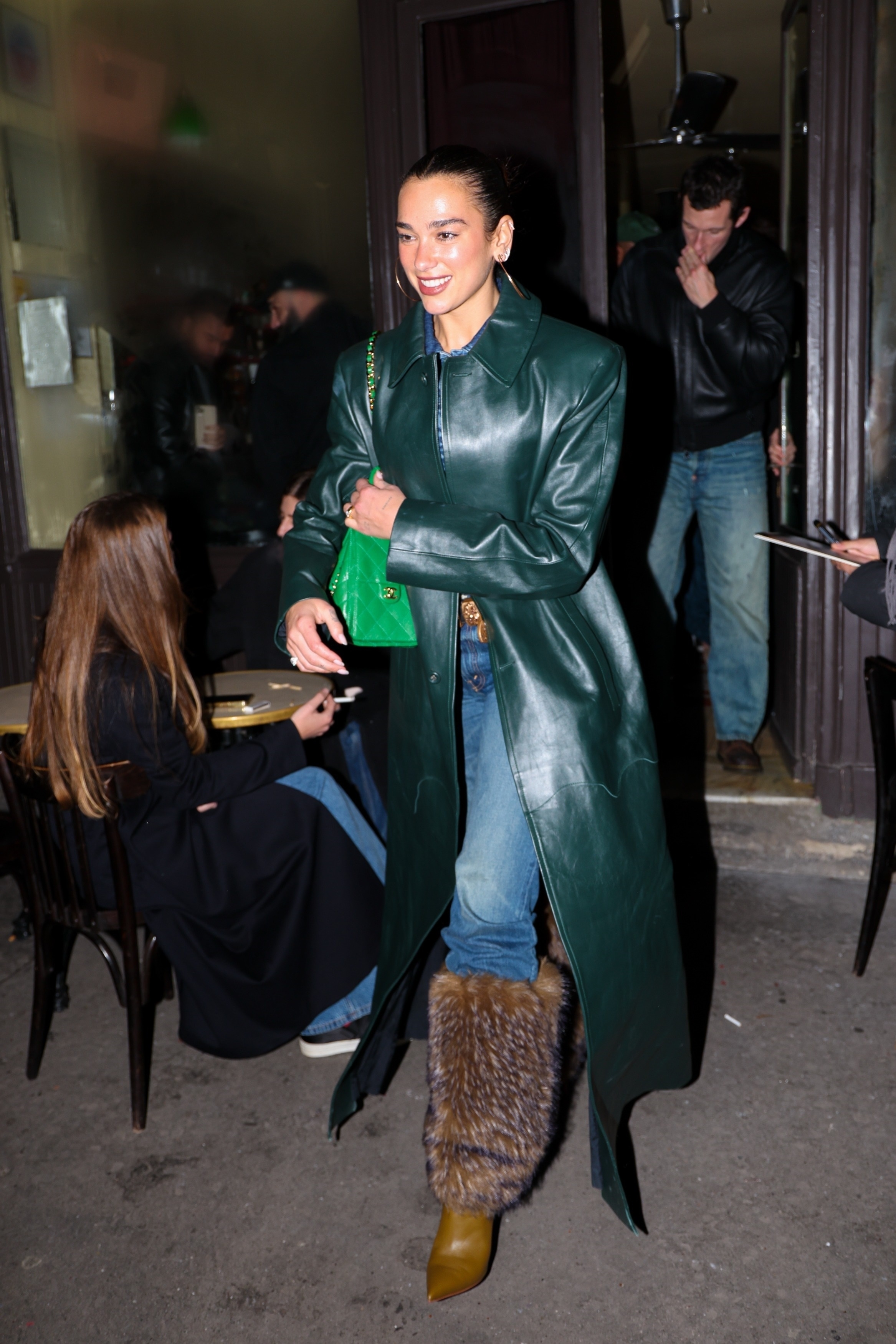 Dua Lipa was spotted in Paris wearing a dark green leather coat, skinny jeans, boots with fur, and a Chanel 25 bag