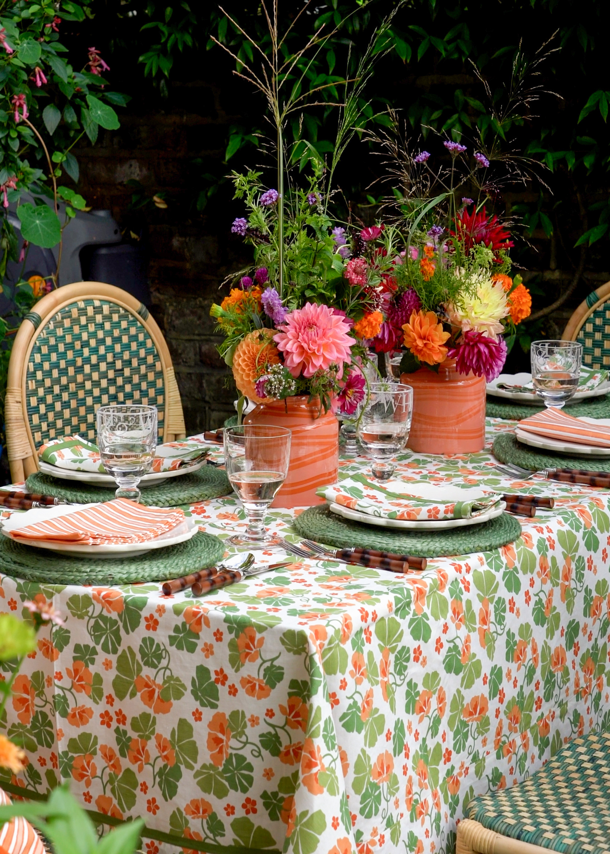 A garden table laid for dinner with a floral tablecloth