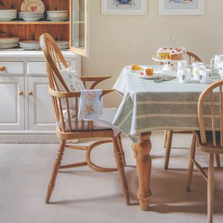 A wooden dining table and chairs with a striped tablecloth