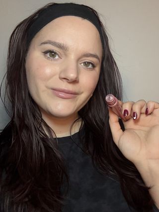 Brooke Knappenberger marie claire associate commerce editor holding up laneige glaze craze tinted lip serum in cinnamon sugar with cap off