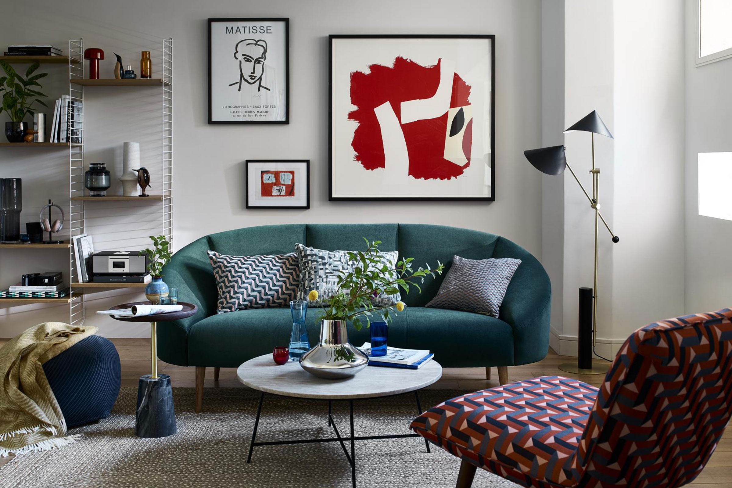 How to position a couch for a small living room, with a curved teal velvet sofa in a neutral scheme with gallery wall.