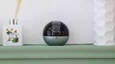 EZVIZ E6 3K camera sitting on a shelf next to a scent diffuser