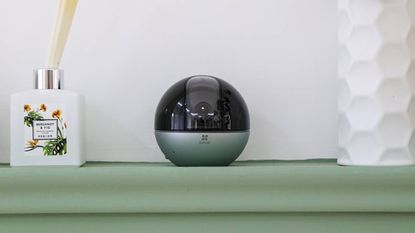 EZVIZ E6 3K camera sitting on a shelf next to a scent diffuser