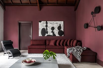 A maroon living room with a white artwork