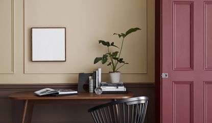 A home office with tan walls and a red door