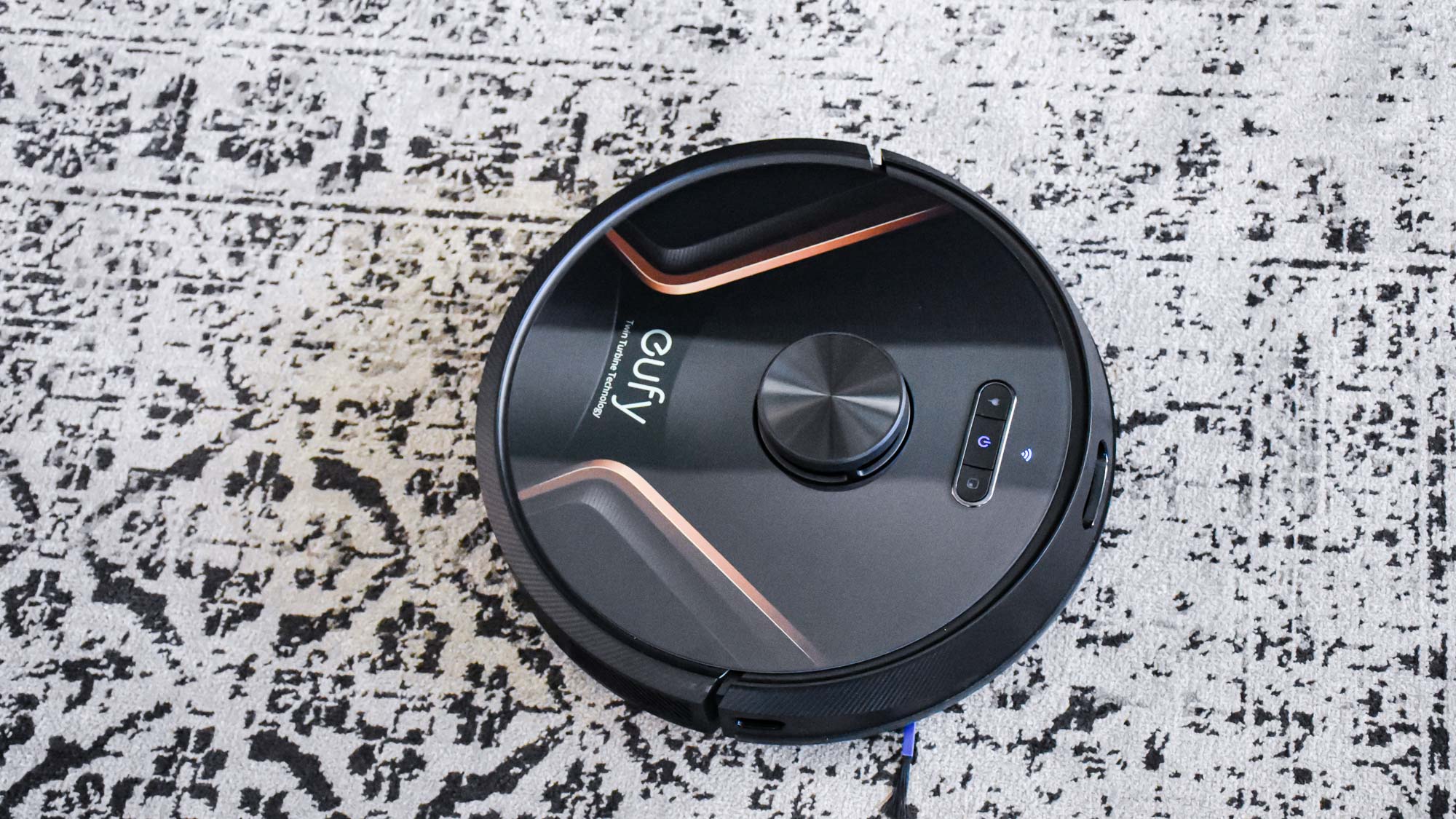 A Eufy RoboVac X8 Hybrid on black and white patterned carpet