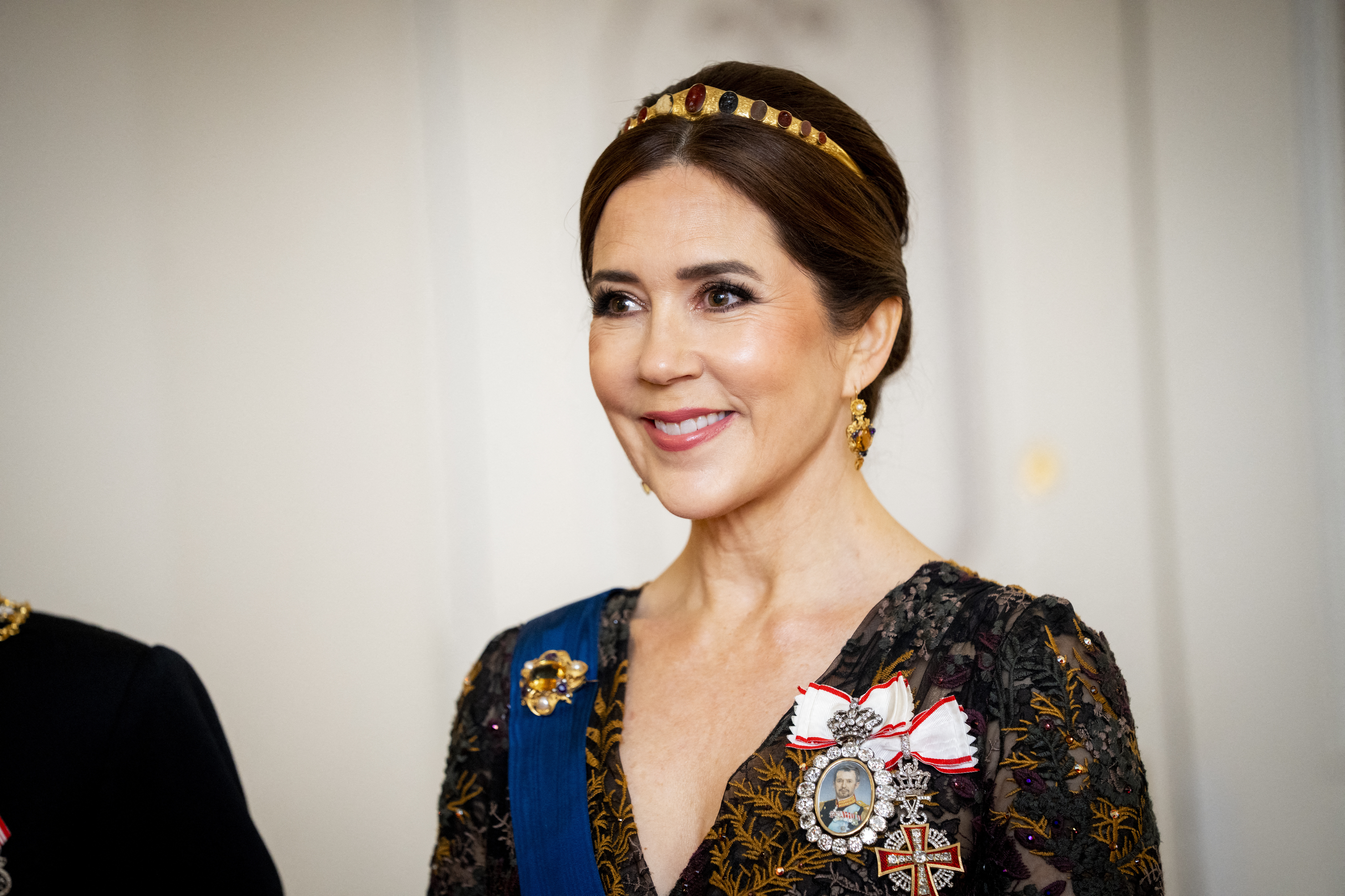 Queen Mary wearing a gold tiara and a vneck emboridered black gown