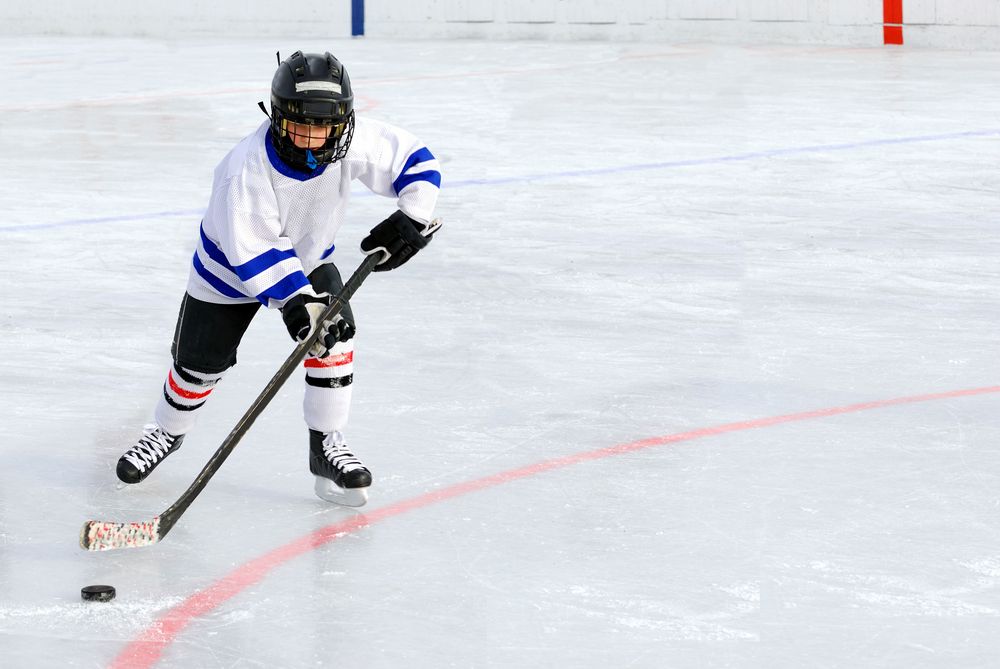 A boy plays hockey on an ice rink