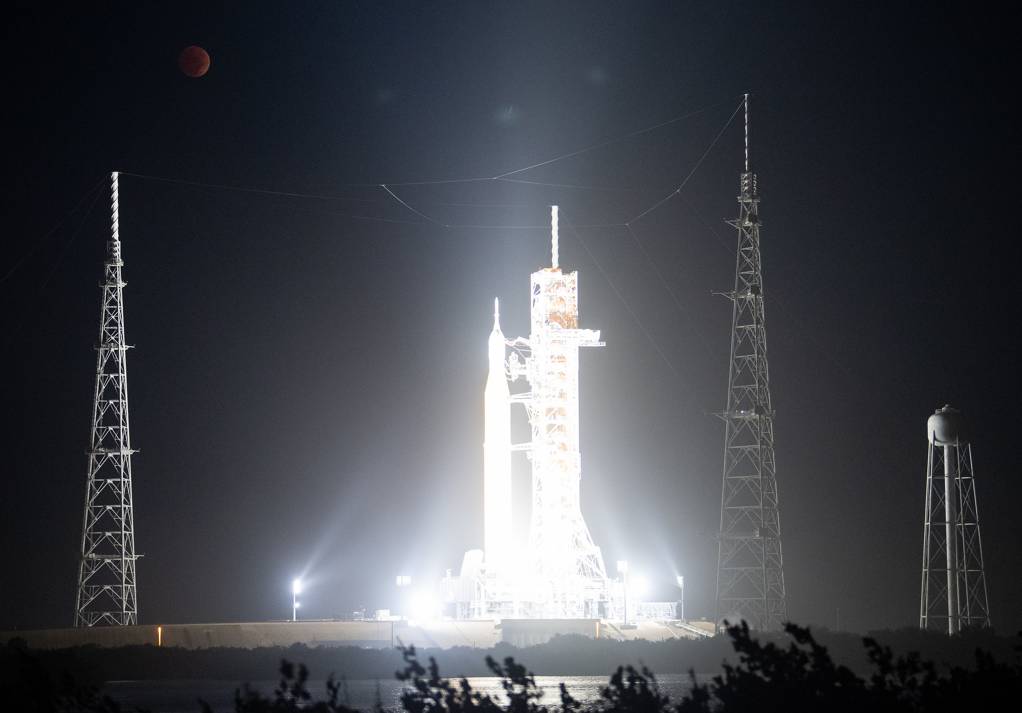 NASA's Artemis 1 lunar rocket is illuminated under the gaze of a blood-colored full moon.