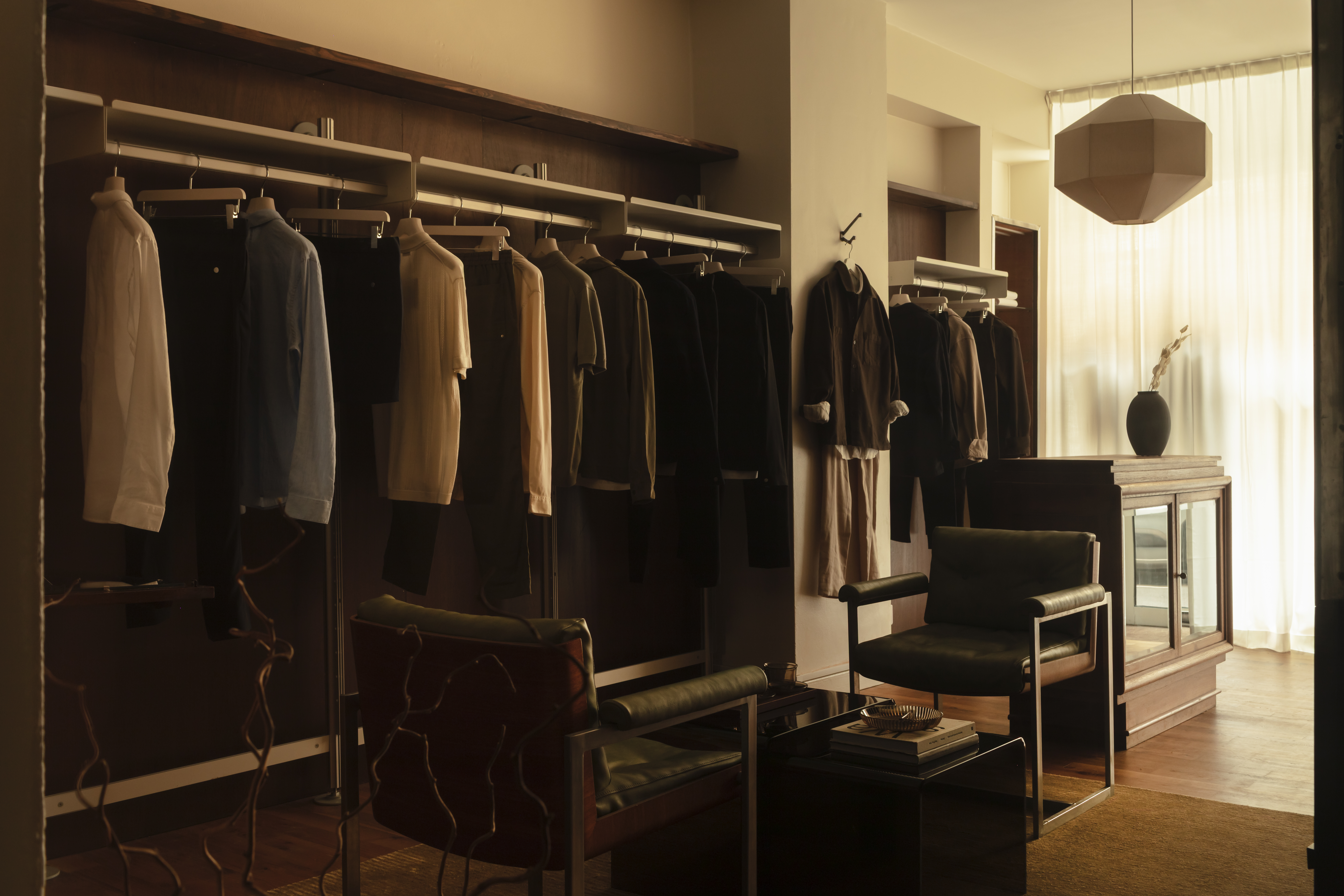Different corners of a sleek menswear store clad in warm woods, beige drapery, and silver and mint green accents.