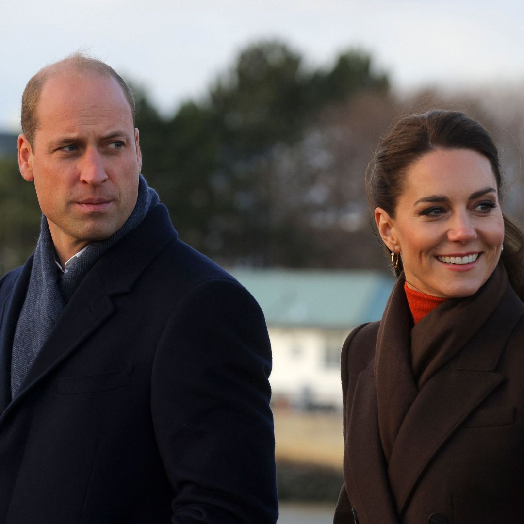 Kate Middleton wearing a brown coat and smiling next to Prince William 