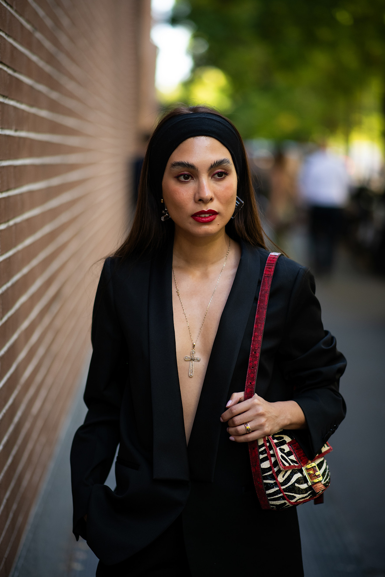 a woman with dark brown hair and red lipstick in a black blazer
