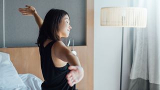 Woman stretching and smiling, getting out of bed in the morning