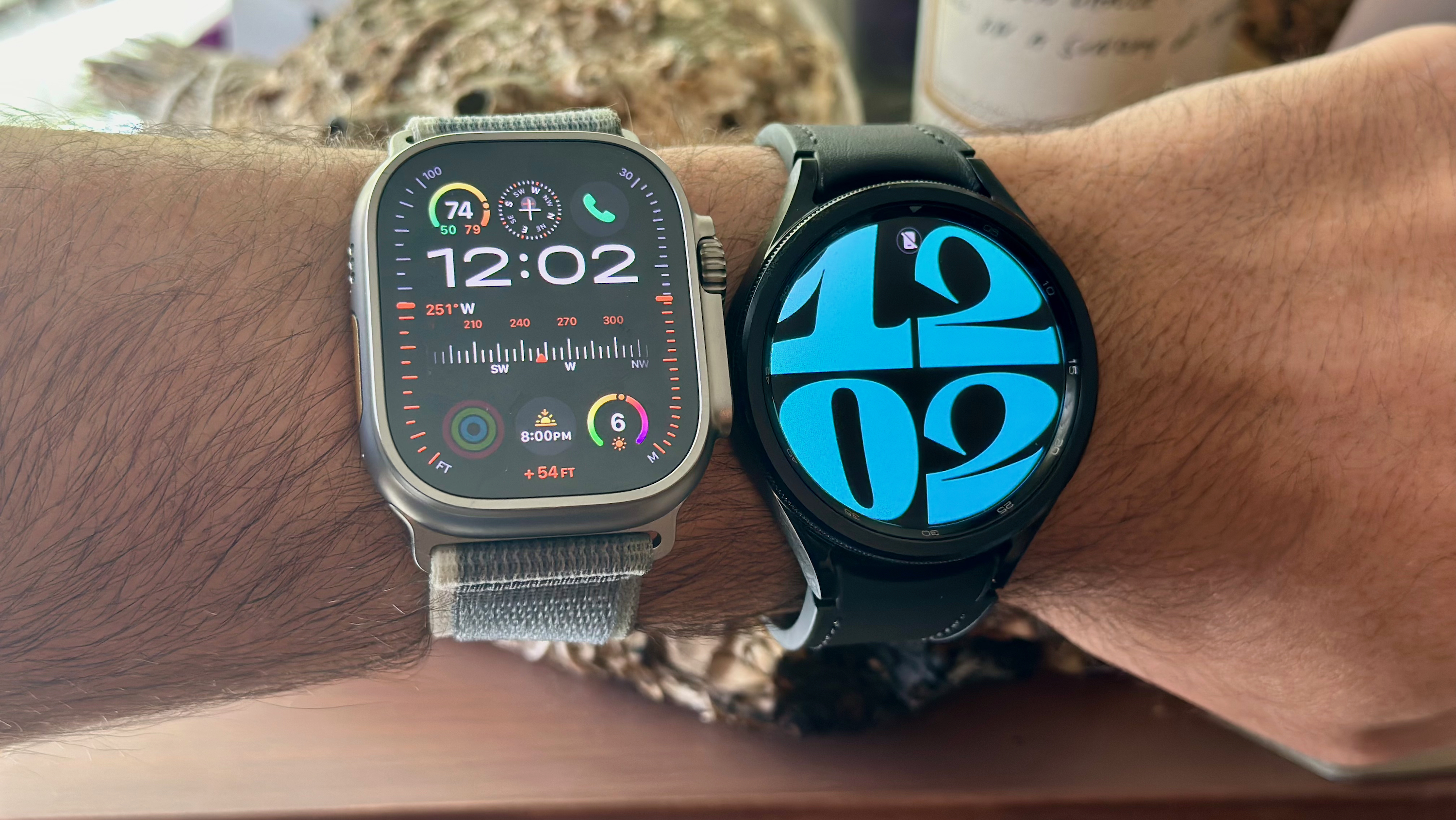 The Apple Watch Ultra 2 (left) and the Samsung Galaxy Watch 6 Classic (right) worn on one wrist.